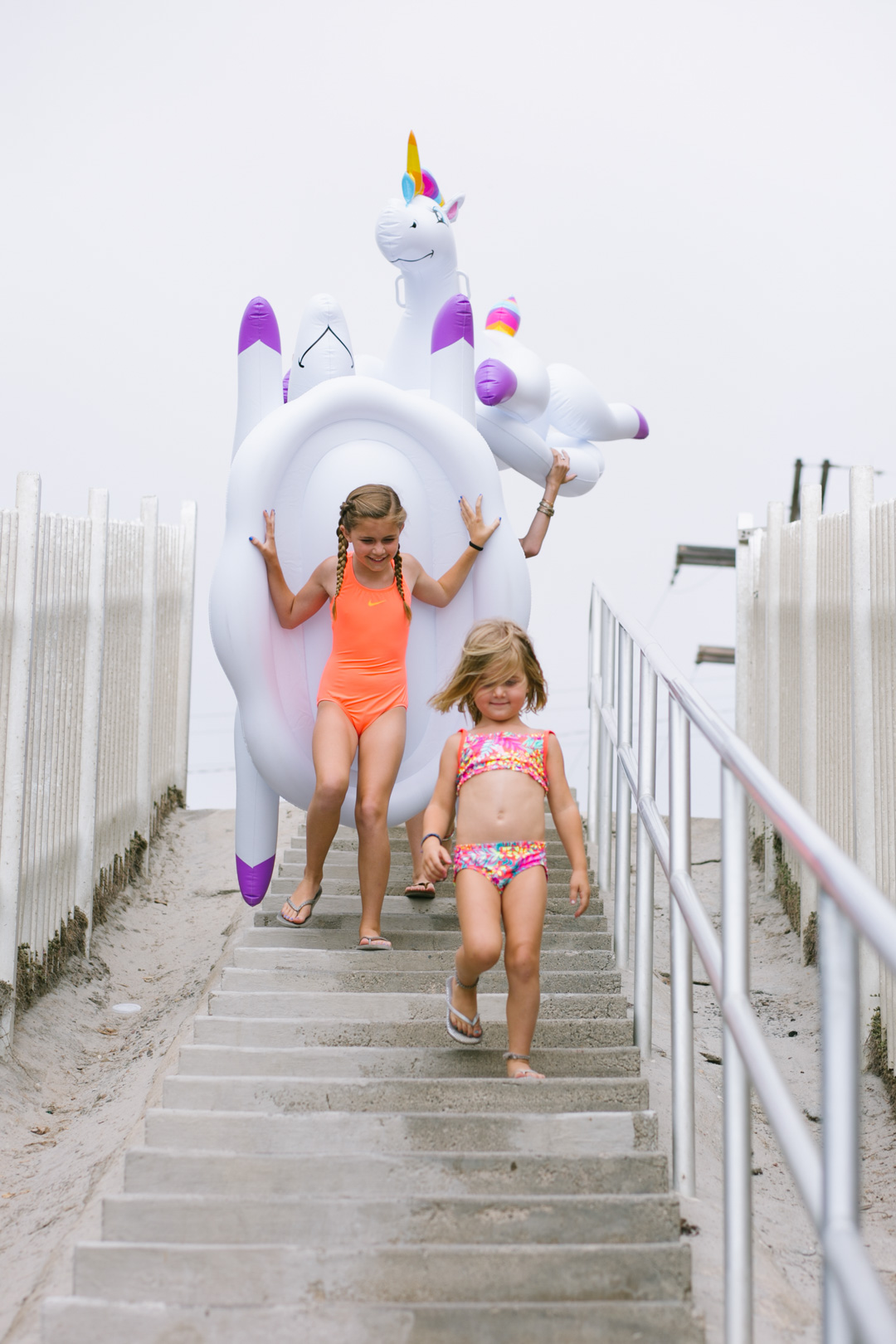 Lisa Allen of LunchPails and Lipstick with her daughters in Solana Beach, CA wearing colorful swimsuits for kids and a unicorn pool float from Kohls