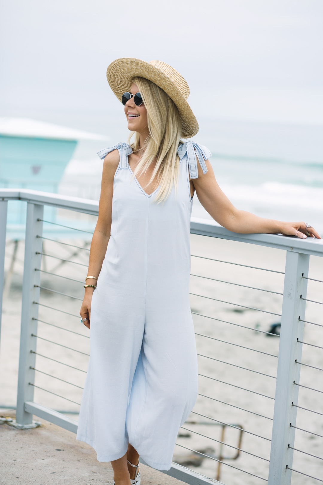 Lisa Allen of Lunchpails and Lipstick wearing a chambray romper, straw boater hat, and silver sandals from Topshop on the beach in CA