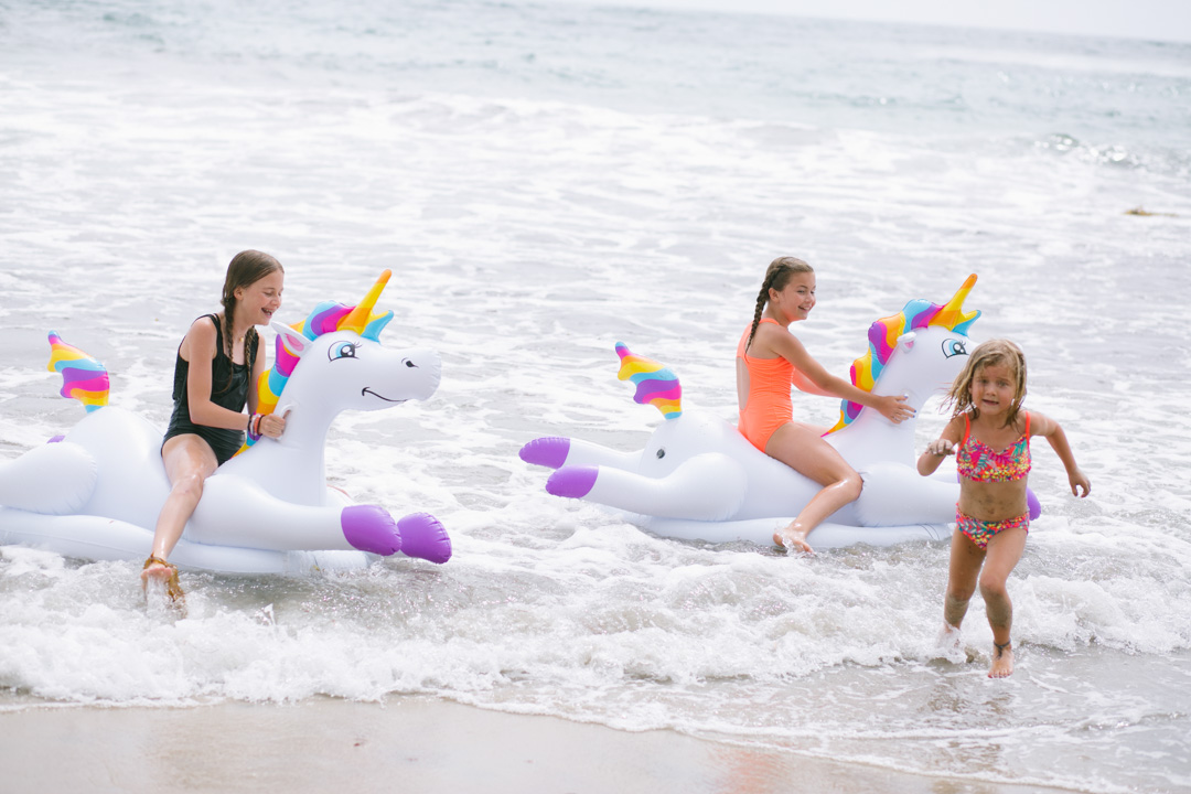 Lisa Allen of LunchPails and Lipstick with her daughters in Solana Beach, CA wearing colorful swimsuits for kids and a unicorn pool float from Kohls