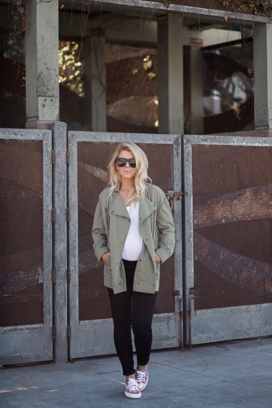 Lisa Allen of LunchPails and Lipstick wearing a green army jacket from amuse society with rose gold sneakers and madewell maternity jeans